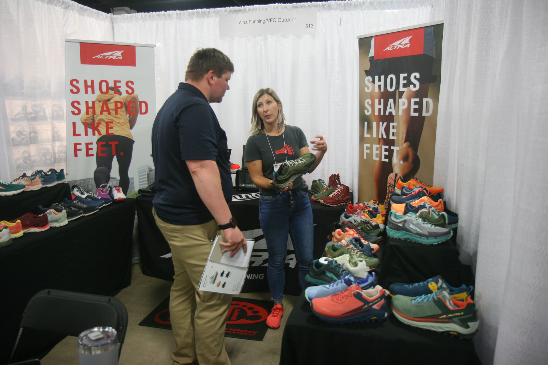 Person showing Altra brand shoes at an exhibit booth